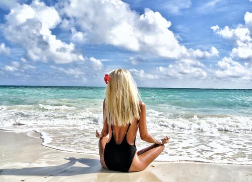 Блондинка медитирует на берегу моря