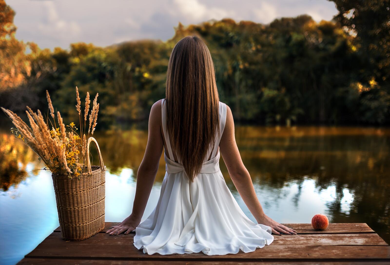 Бесплатное фото Девушка сидит на деревянном мостике в легком белом платье