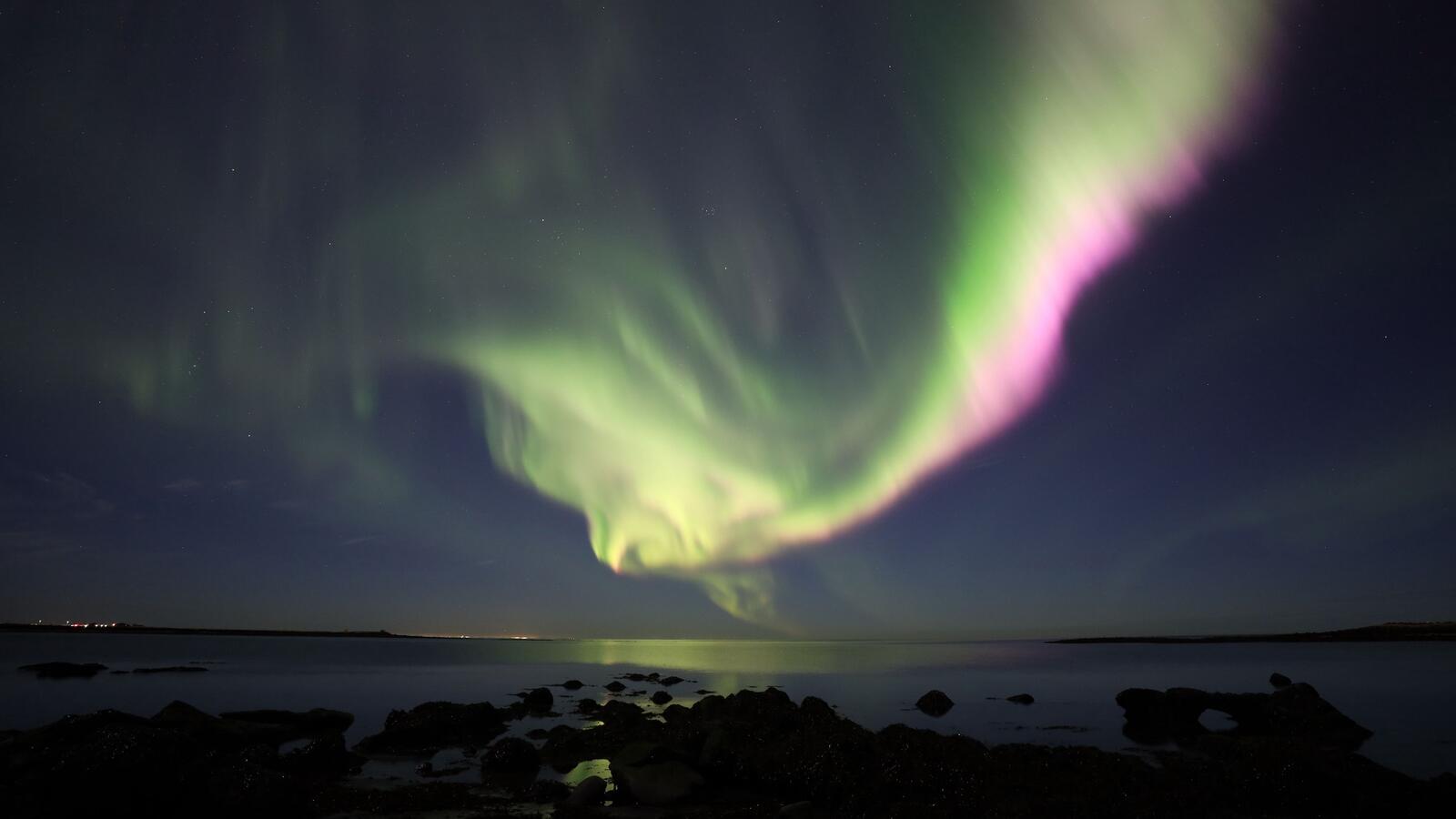 Free photo Bright northern lights over the ocean