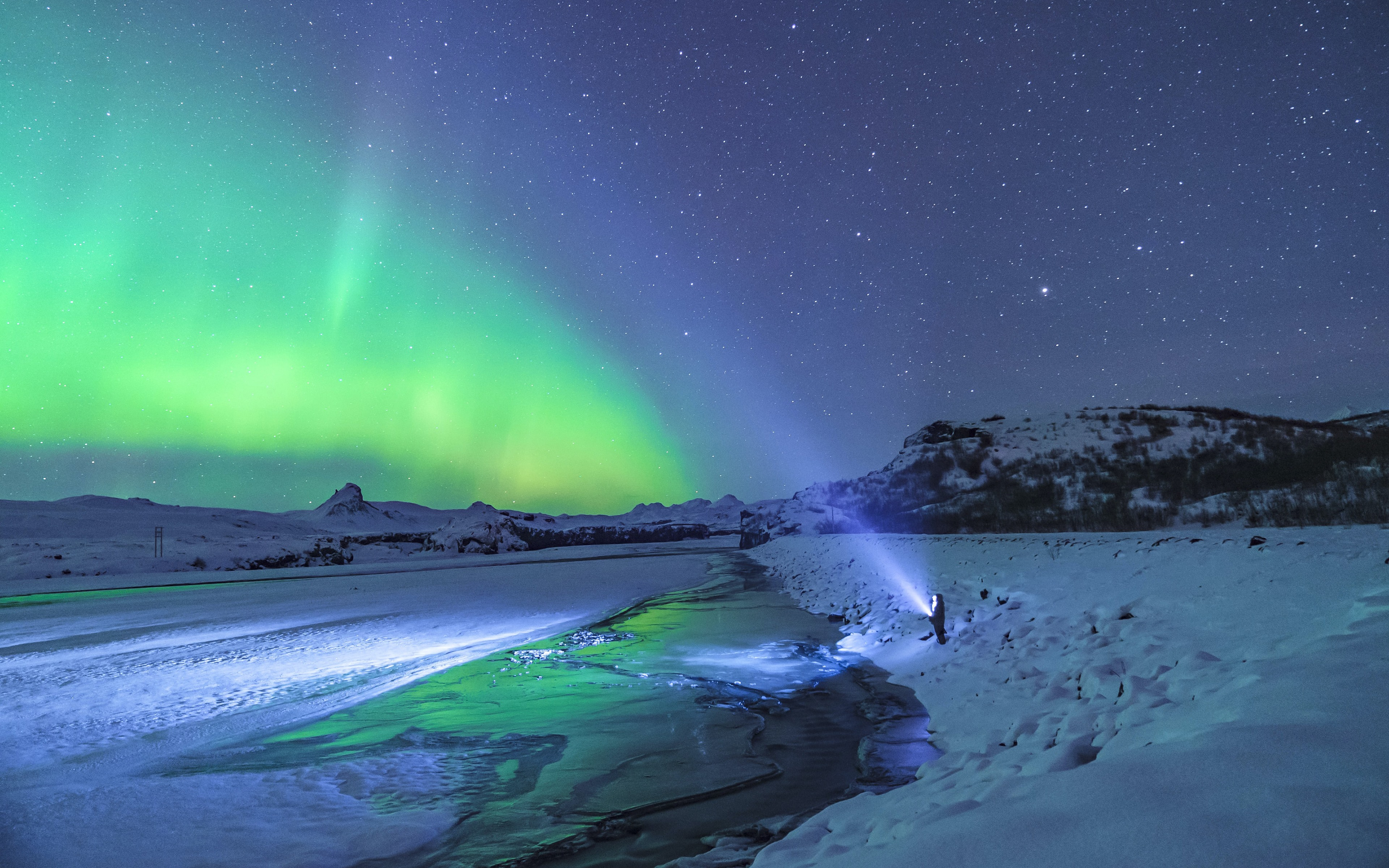 Free photo A man turned on a powerful flashlight into the night sky with the northern lights