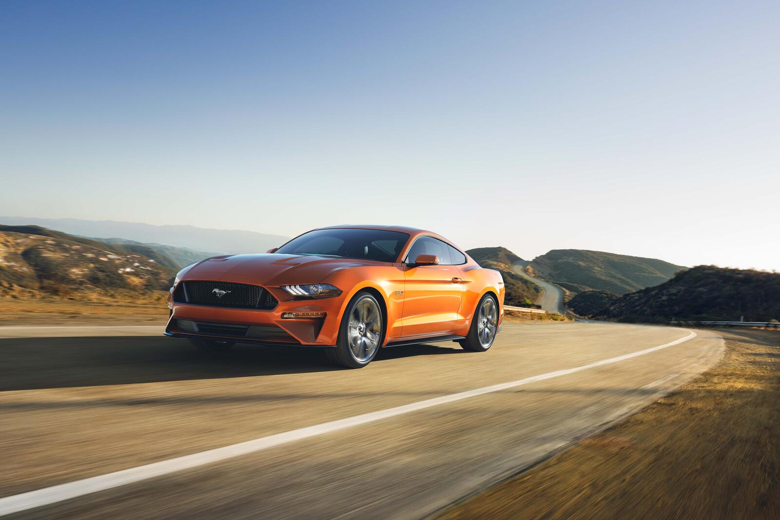 Бесплатное фото По загородной дороге едет оранжевый Ford Mustang