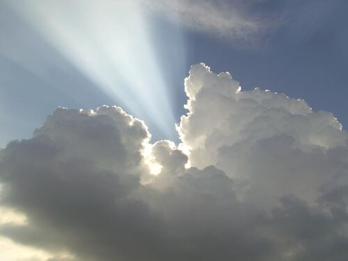 A bright ray of sunlight breaks through a thick cloud