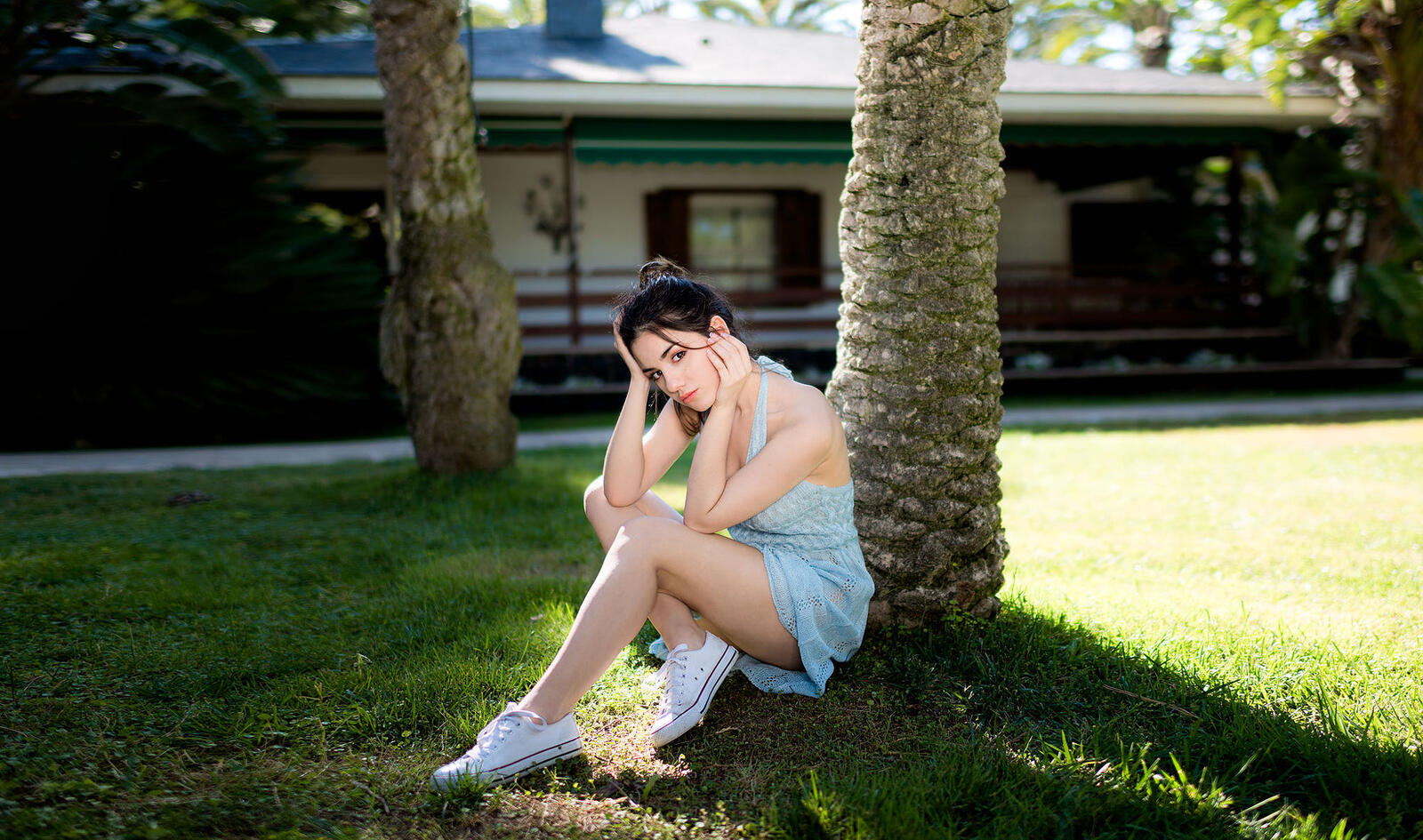 Бесплатное фото Делайя Гонсалес в легком платье сидит под деревом