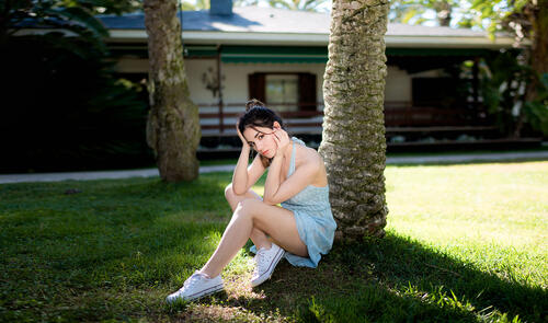 Делайя Гонсалес в легком платье сидит под деревом