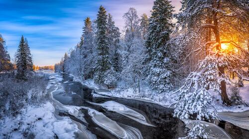 A creek with snow banks in the woods at sunset