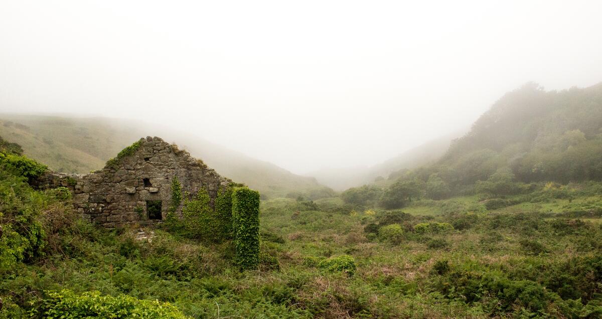 Руины каменного дома в долине у холма