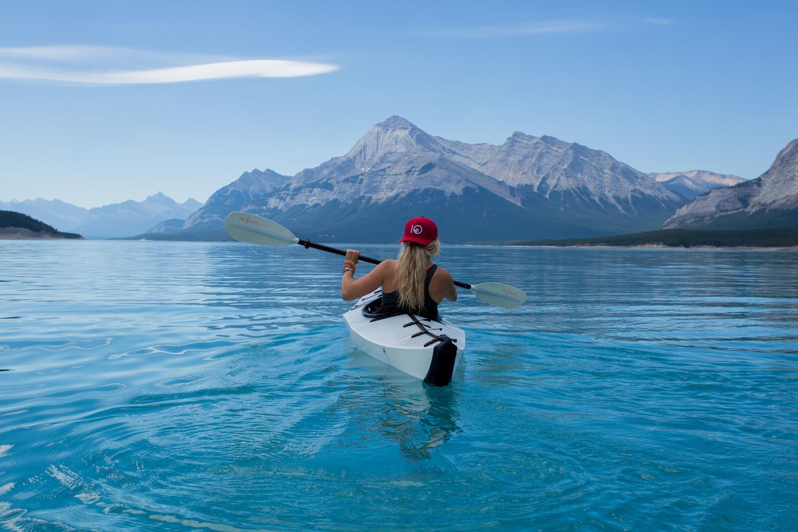 免费照片一个女孩在碧蓝的水面上划着皮艇