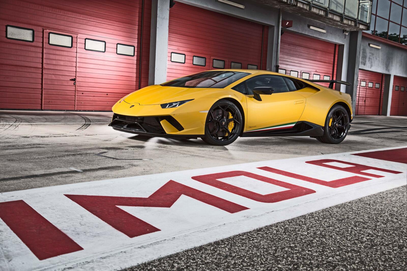 Бесплатное фото Lamborghini Huracan желтого цвета стоит у ворот гаража