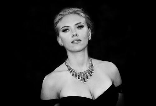 Scarlett Johansson in a black dress against a dark background