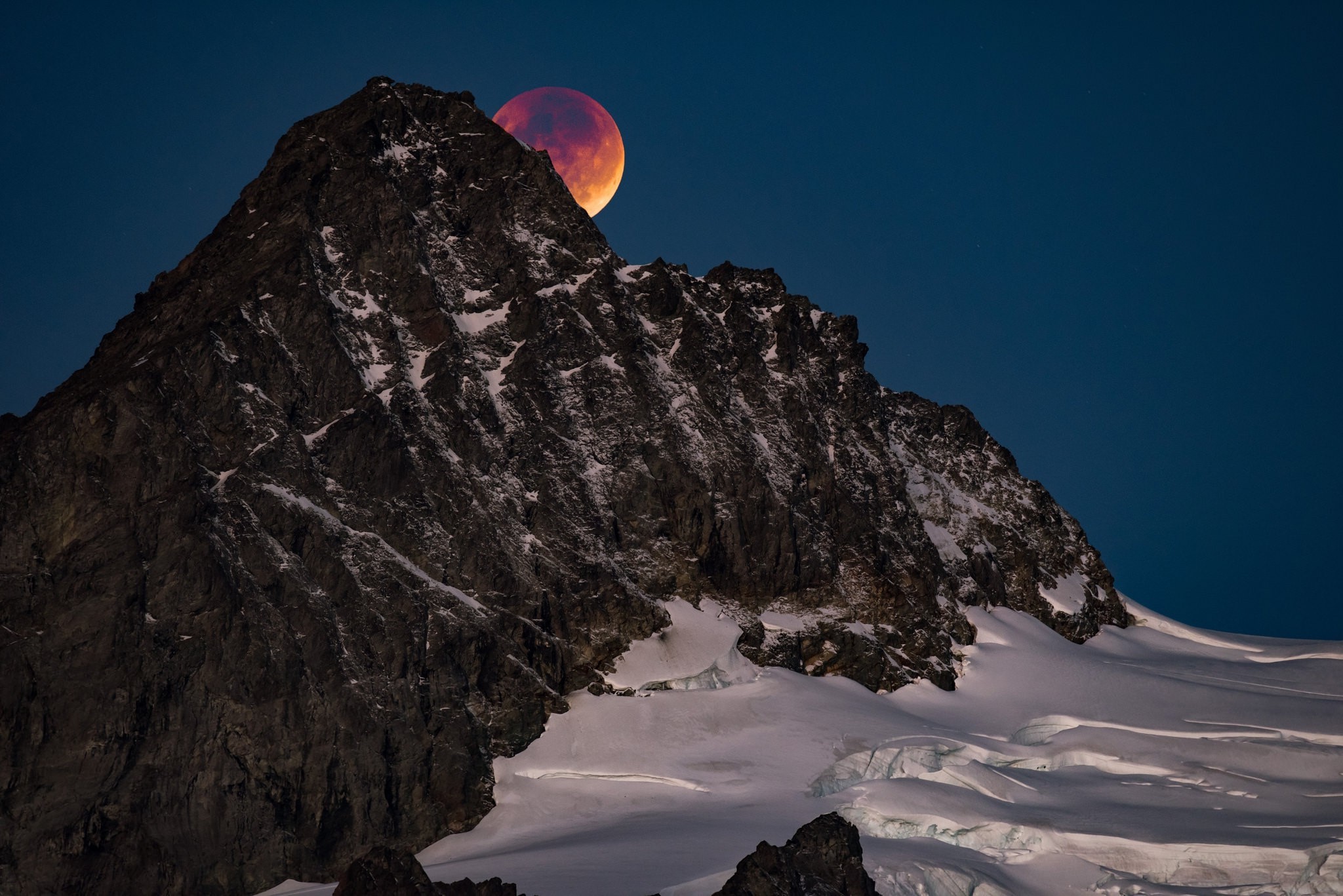 Красная луна прячется за вершину скалы