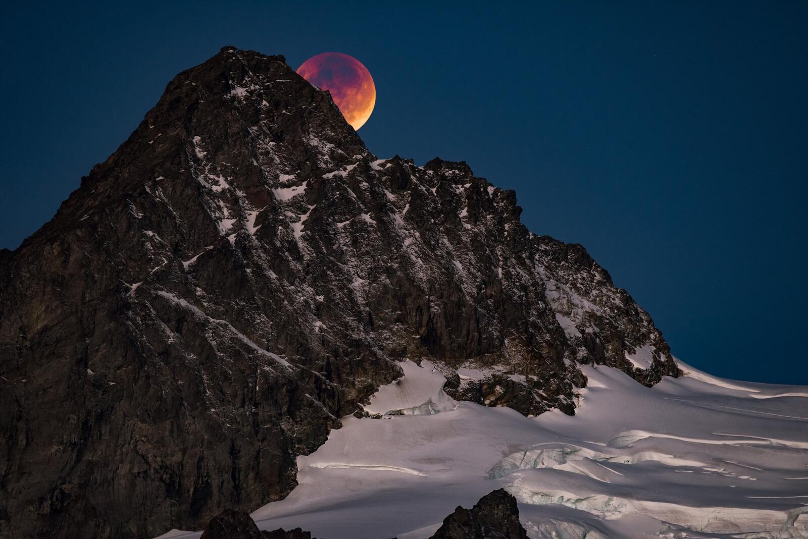 Бесплатное фото Красная луна прячется за вершину скалы