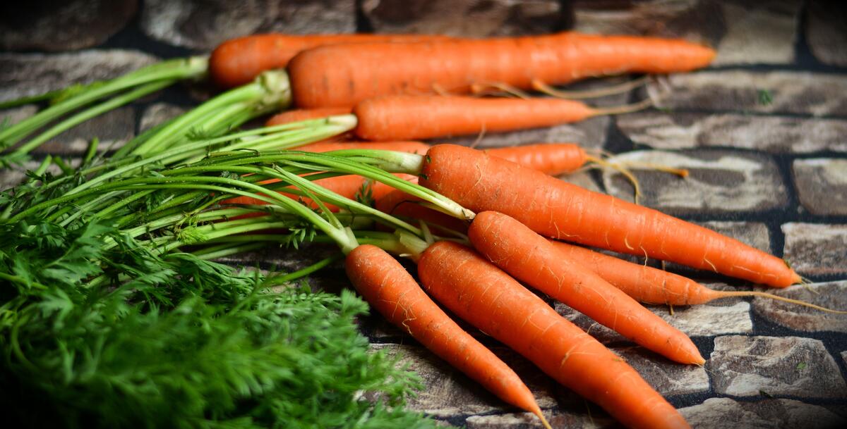 Морковь с зеленью лежат на брусчатке