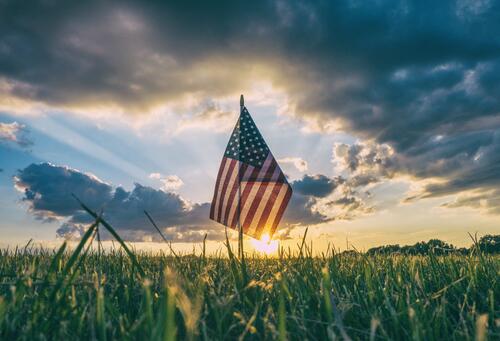 An American flag in a field at sunset
