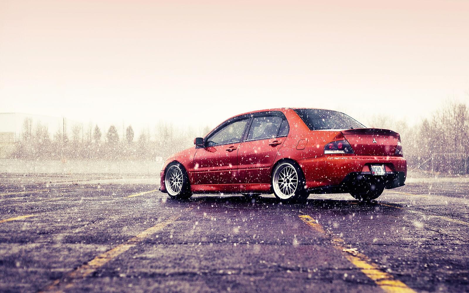 Бесплатное фото Mitsubishi lancer evo красного цвета на дисках BBS в снежную погоду