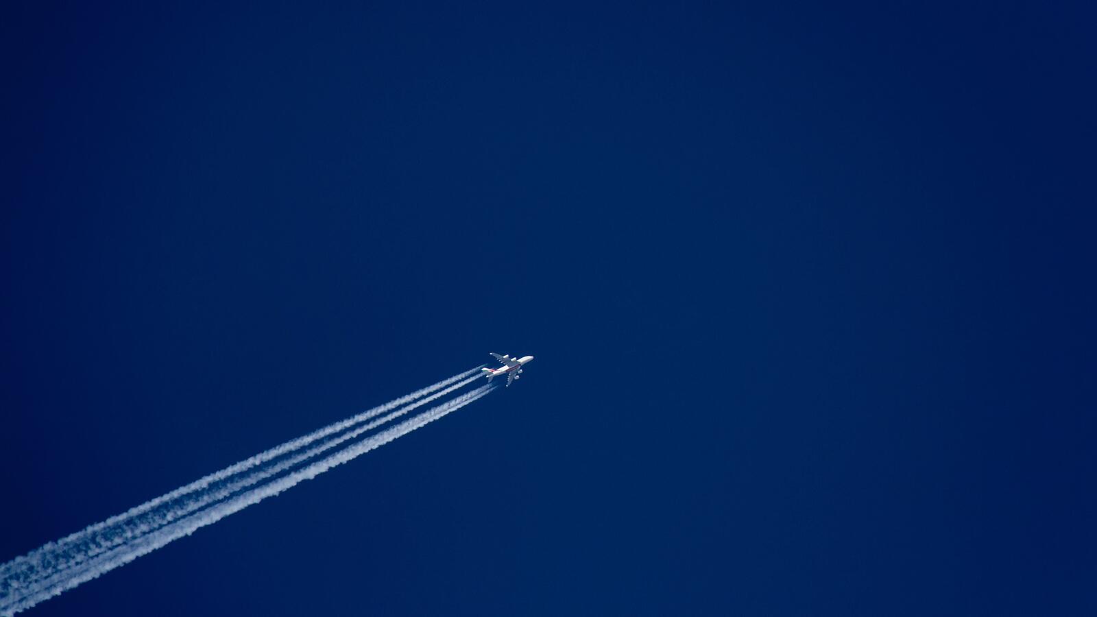 Бесплатное фото Самолет на синем небе оставляет следы от двигателей