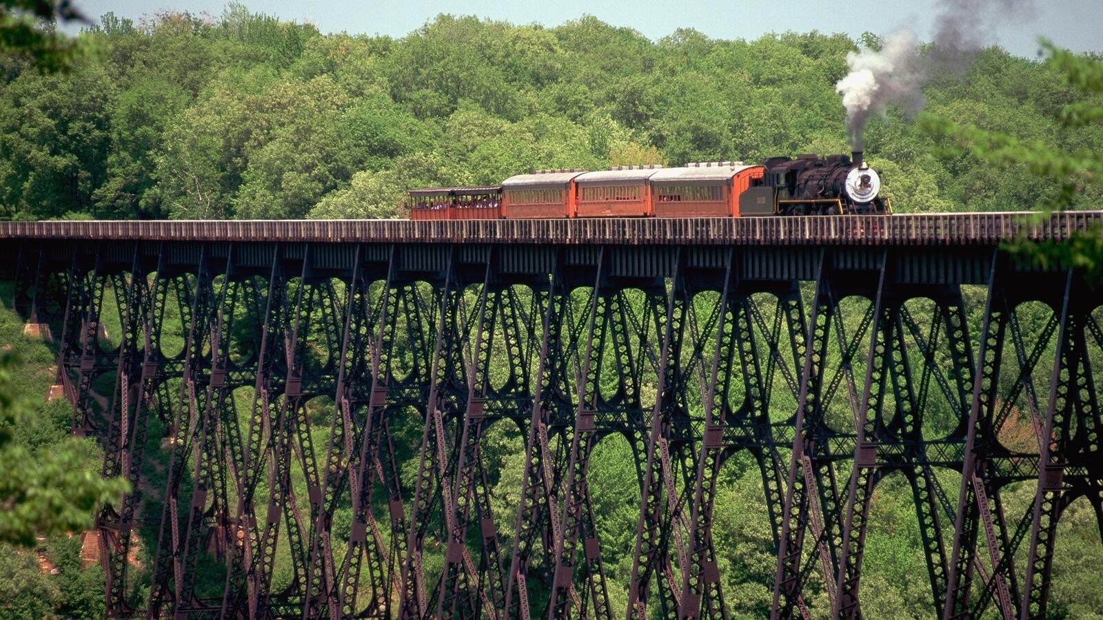Free photo A steam locomotive is traveling over a high bridge