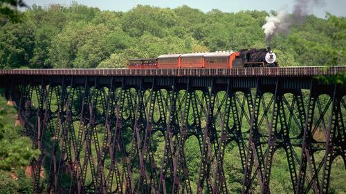 A steam locomotive is traveling over a high bridge