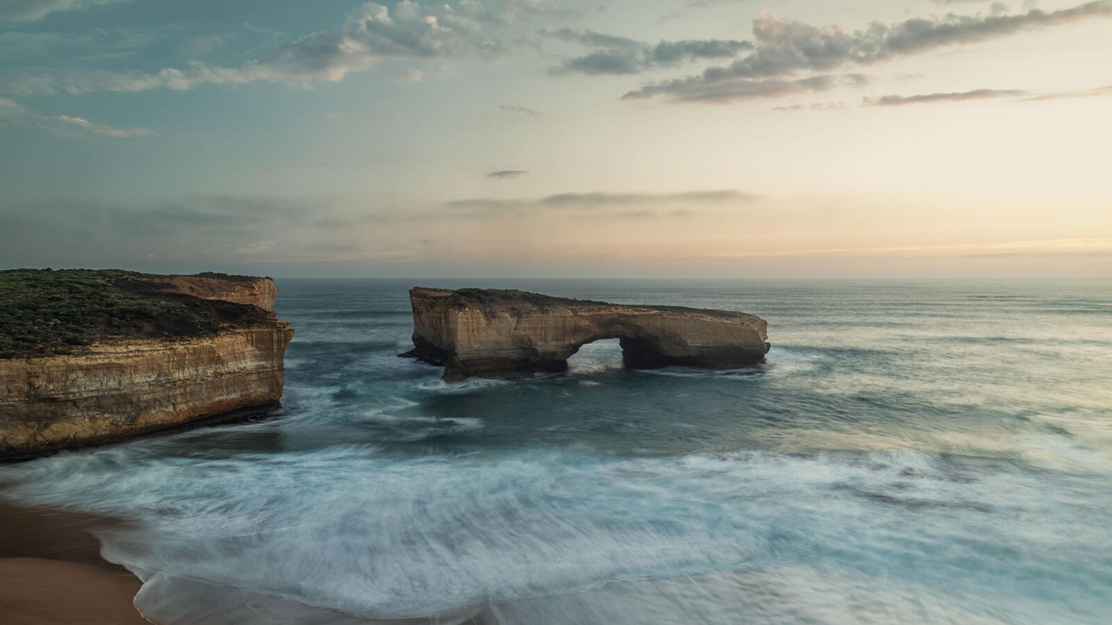 Бесплатное фото Часть скалы с аркой отделилась от большой скалы на глубине моря