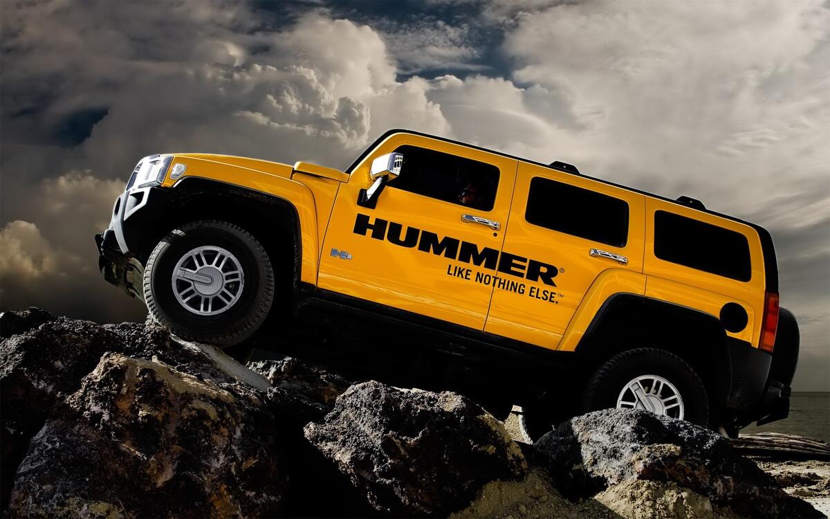 Yellow Hummer H3 going over the rocks.