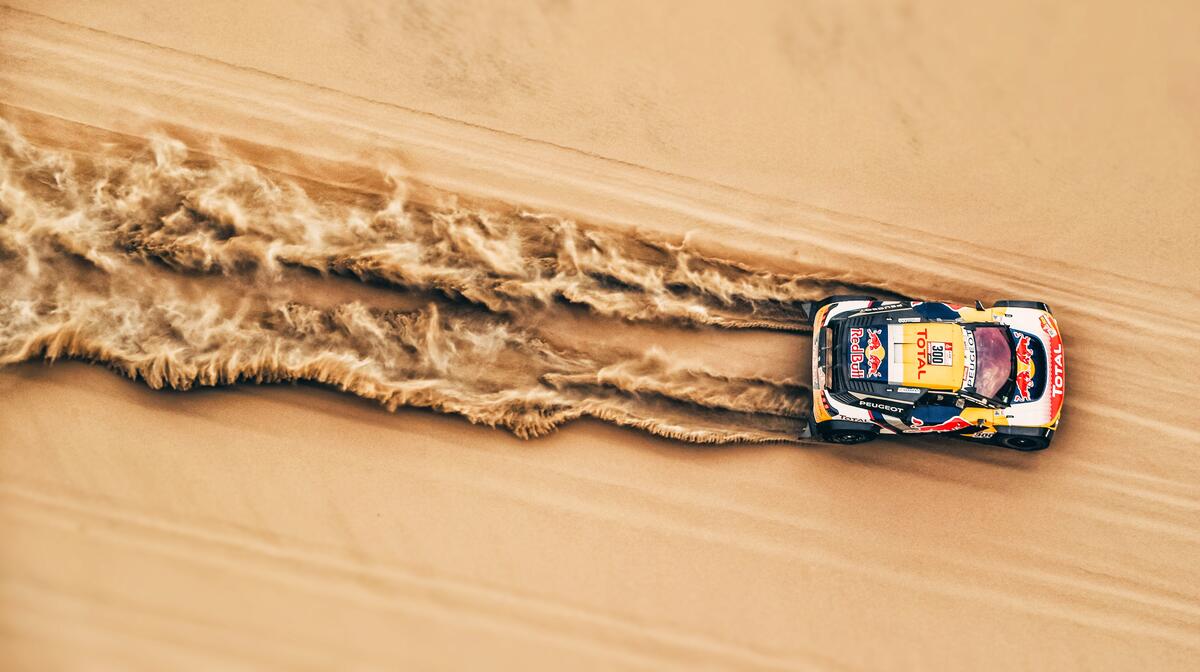 A speeding car rallying in the sand