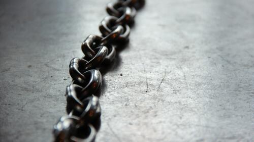 A black chain lies on a metal table