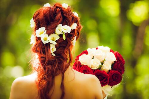 Рыжеволосая невеста с красным букетом роз