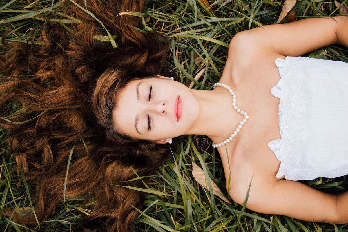 A girl in a white wedding dress lying on the grass