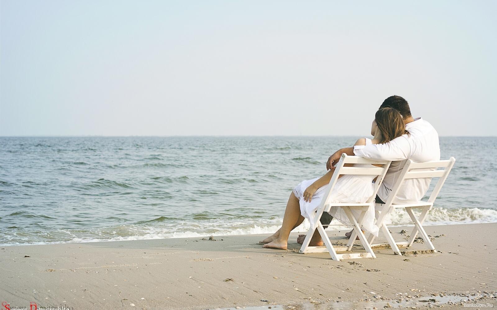 Free photo Couple sitting on the beach sitting on chairs
