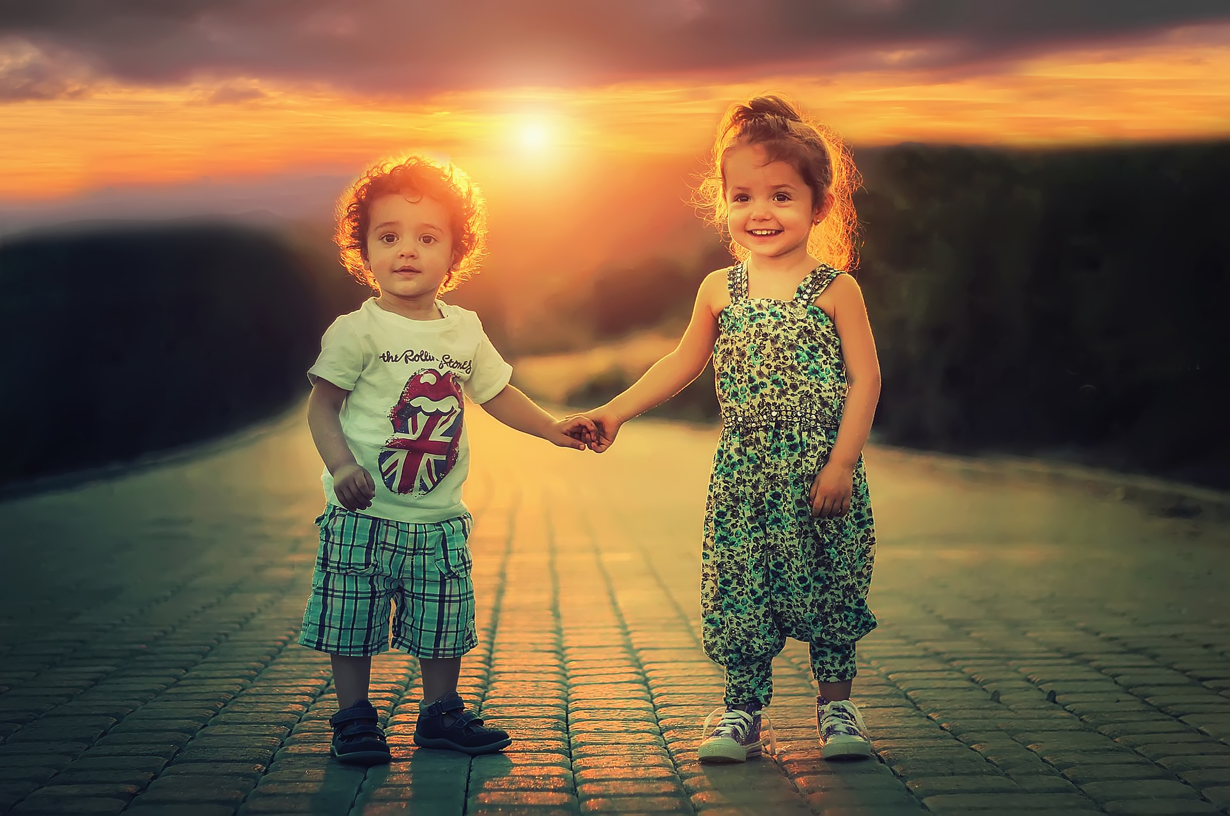 Детки держатся за руку на фоне заката