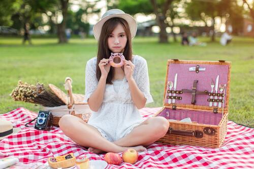 Азиатская девочка на пикнике ест пончик