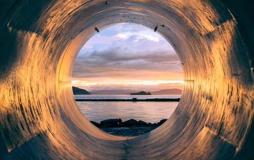 A view of the seashore from a drainpipe