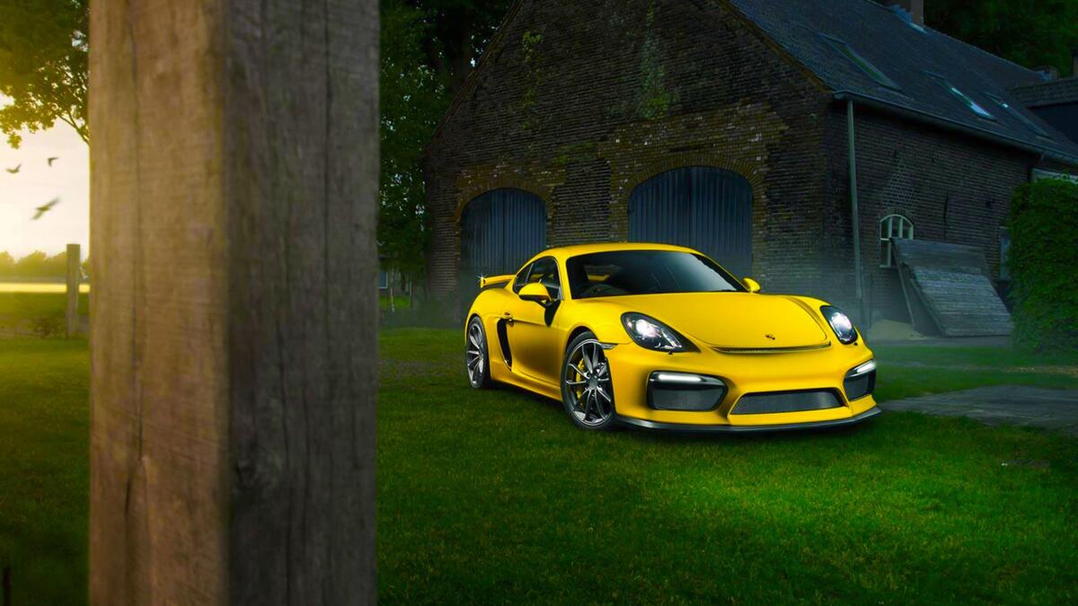 Желтый Porsche Cayman стоит на зеленой лужайке