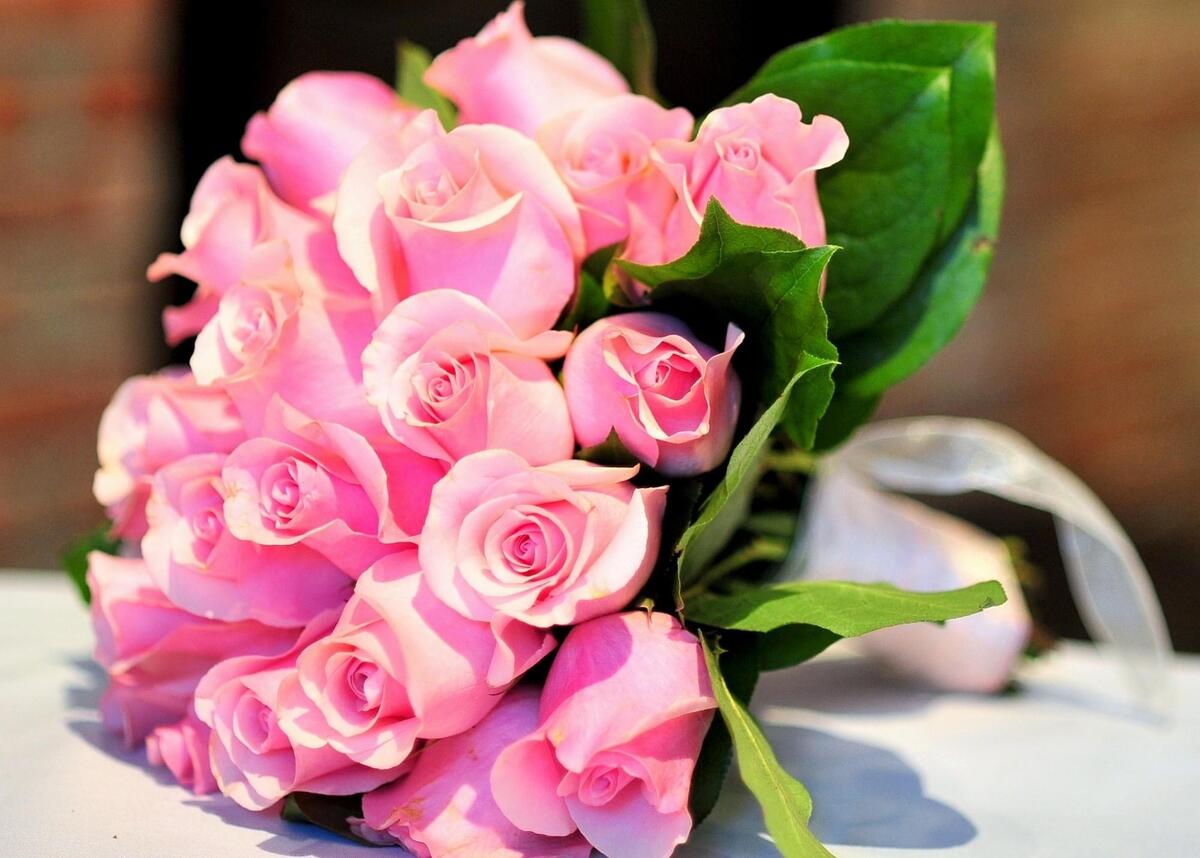 A bouquet of pink roses lies on the table