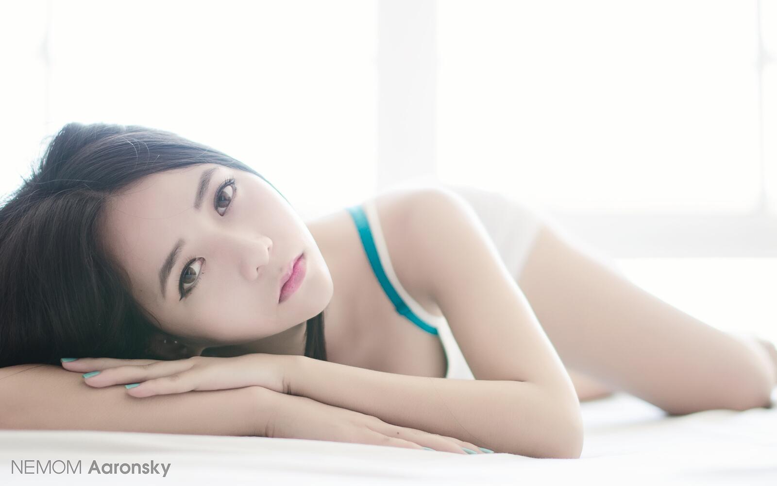 Free photo Asian girl with brown hair lying on her stomach