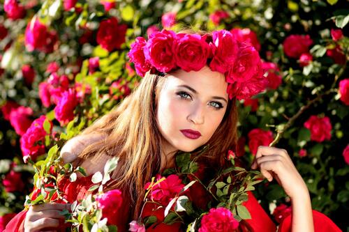 The girl has a wreath of red roses on her head