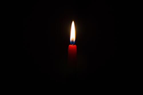 Burning red candle on a black background