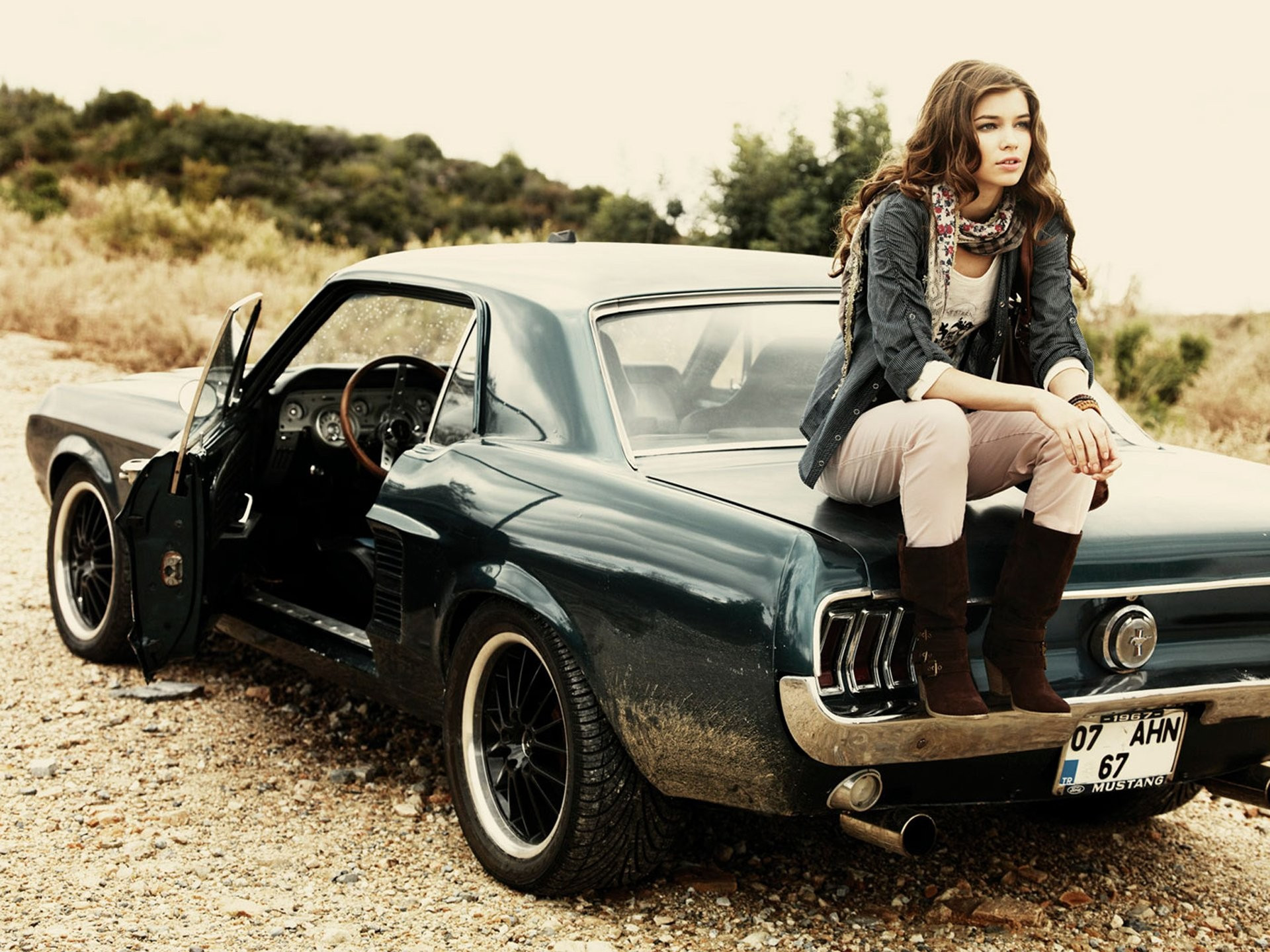 Dark-haired girl sitting on the trunk of a mustang