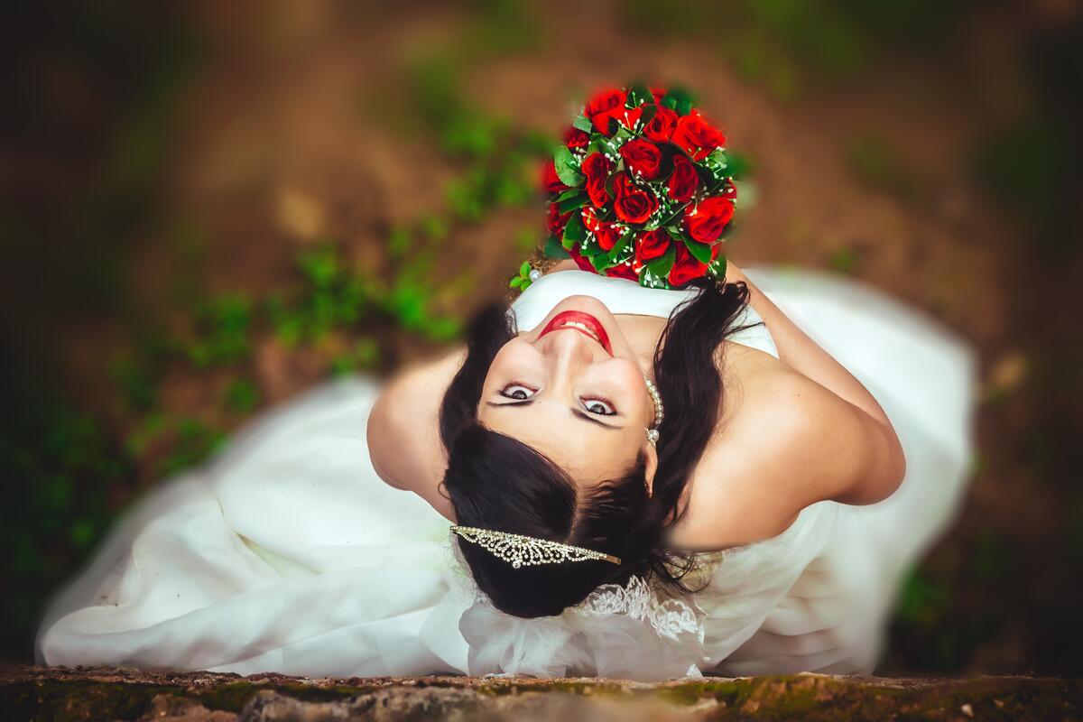 A bride with a red bouquet of roses.