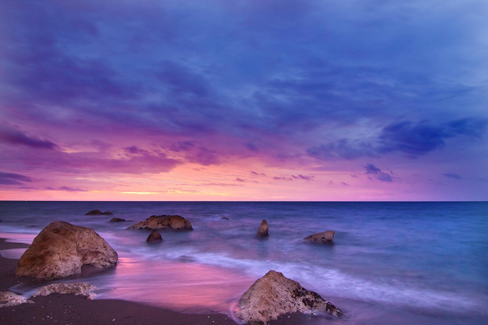 Бесплатное фото Вечерний песчаный берег с камнями в воде