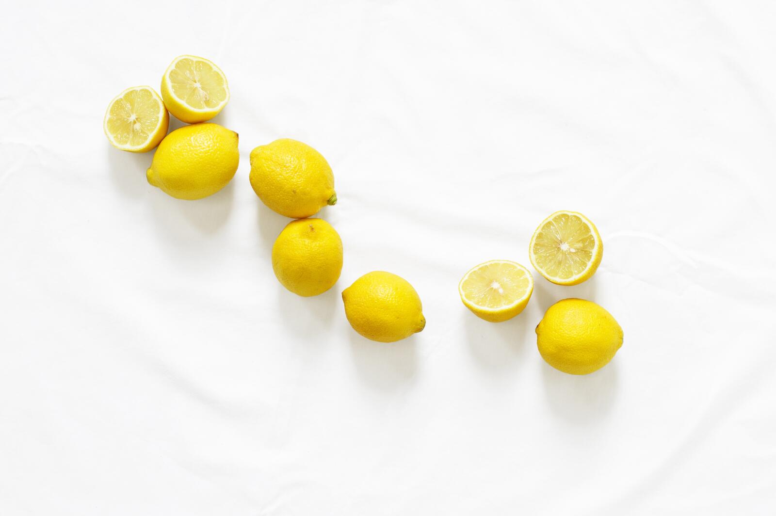 Разбросанный желтый лимон на белом фоне