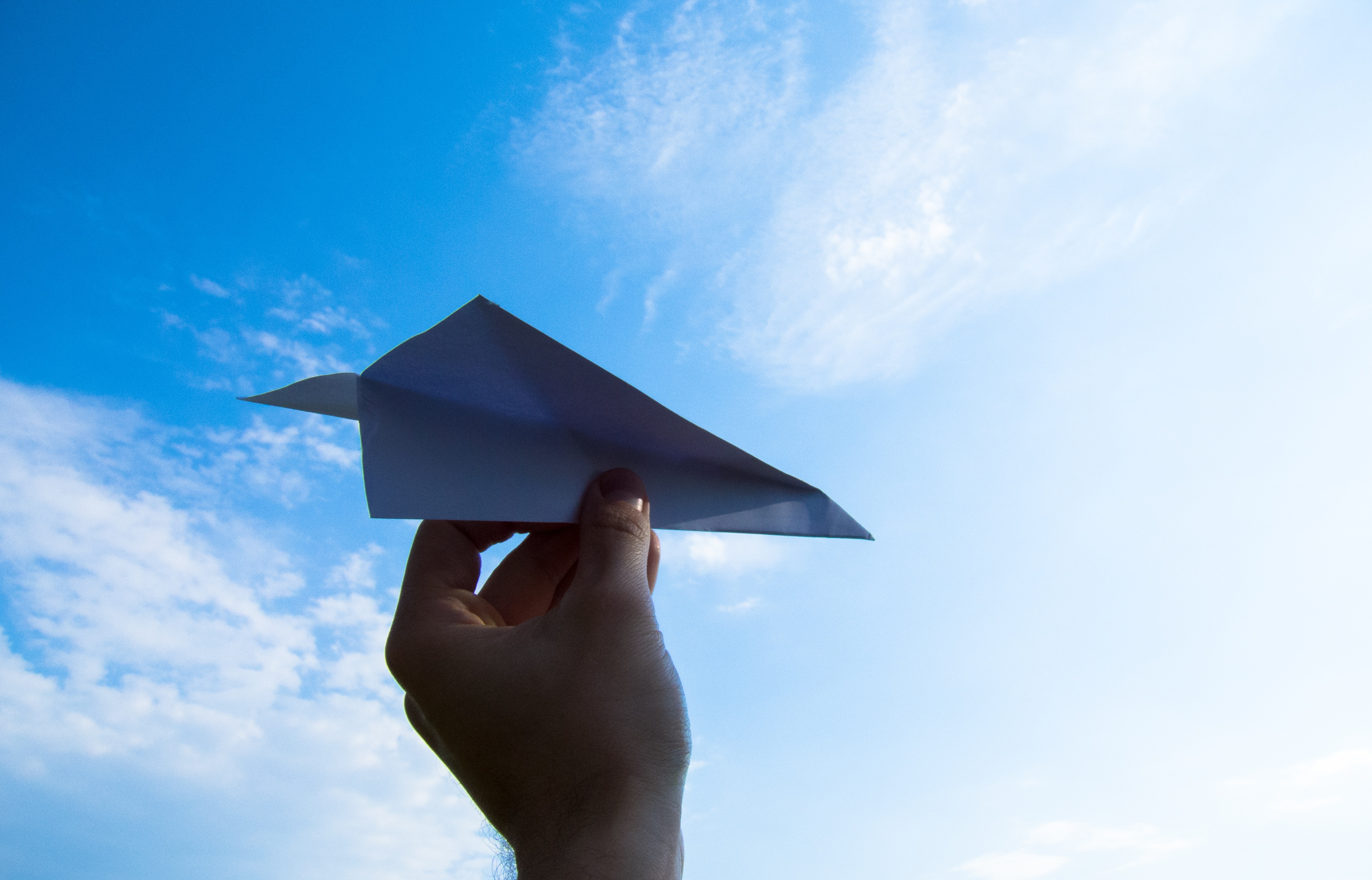 Бумажный самолетик на фоне неба
