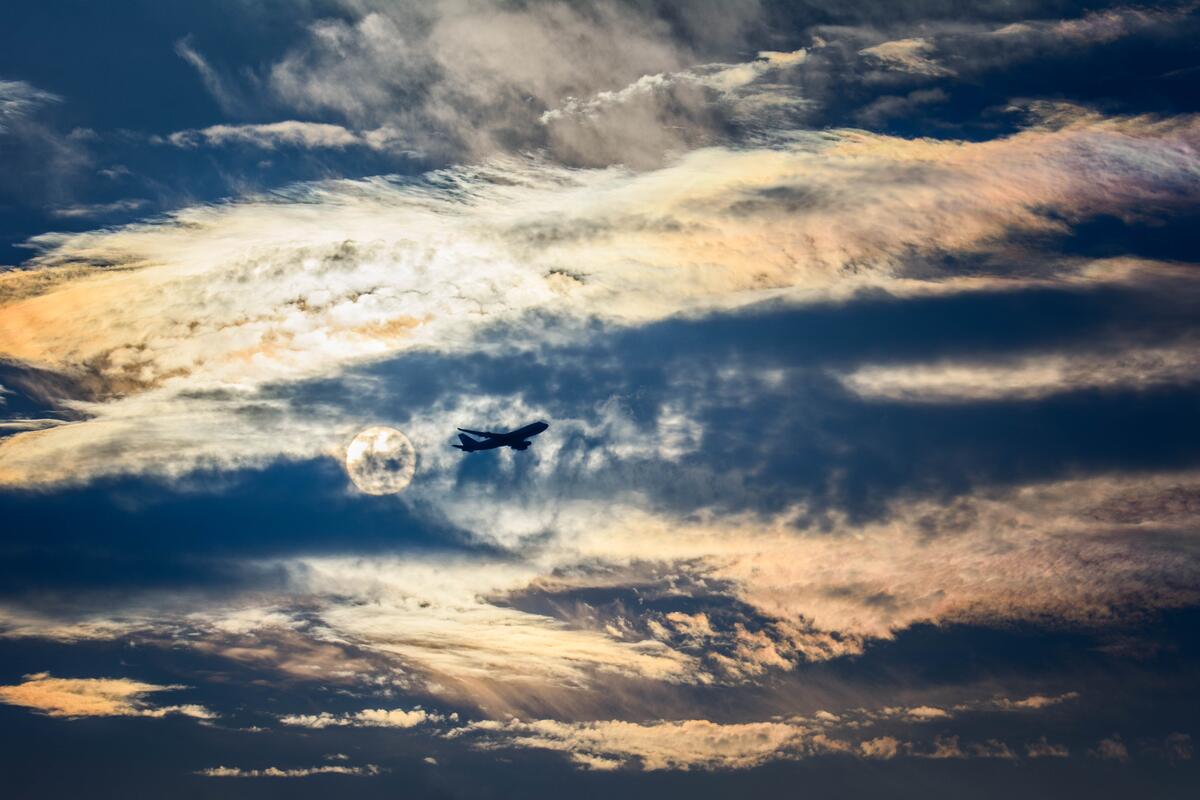 Самолет летящий за облаками на фоне луны