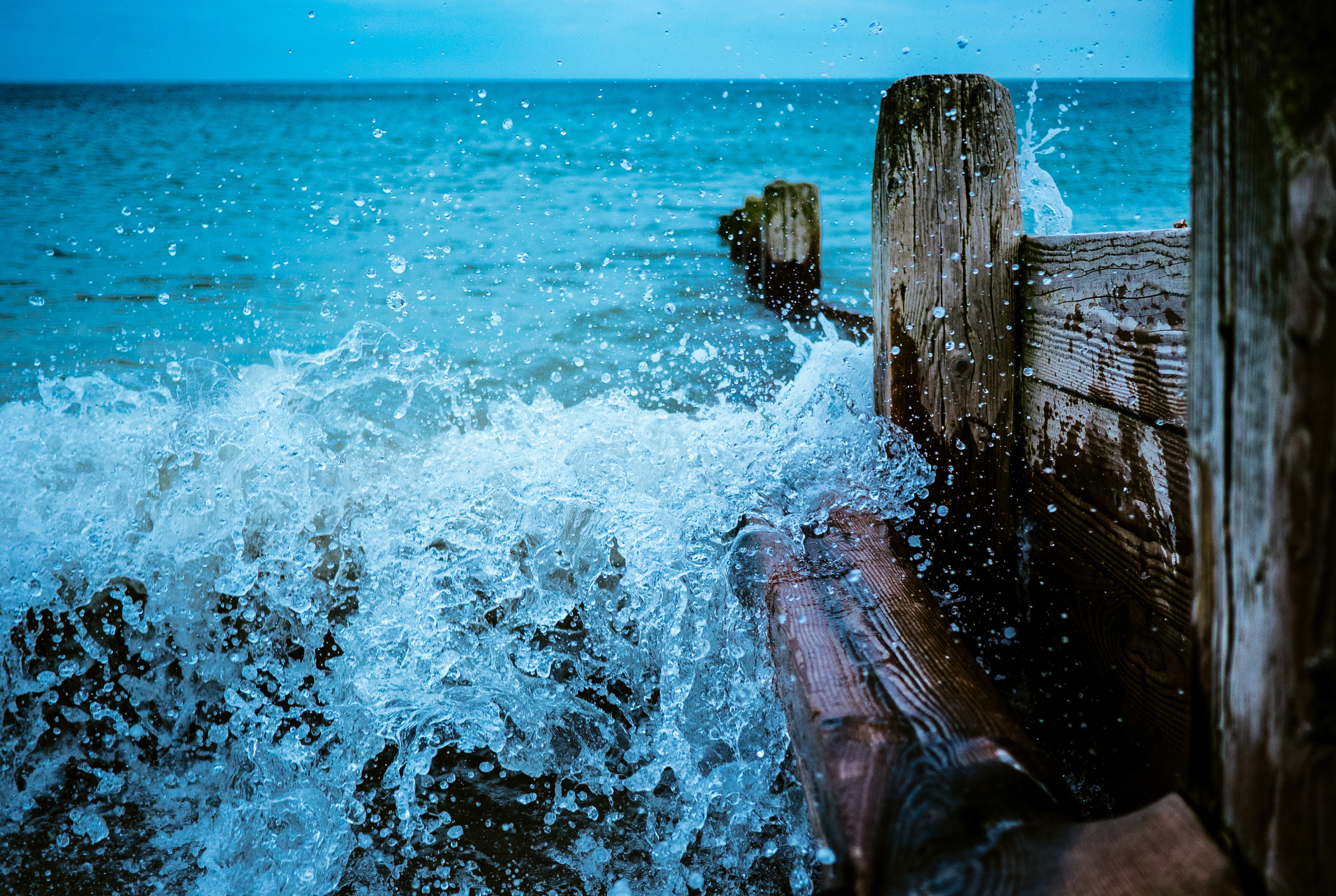 The sea beats against the wooden fence