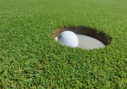 A golf ball falls into the hole