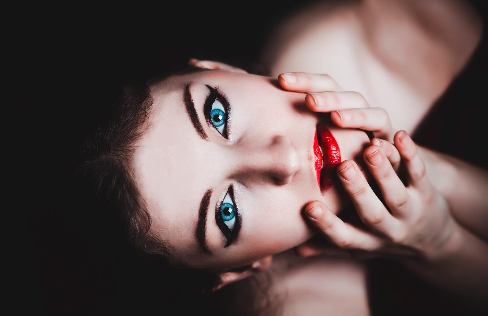 Free photo Girl touches her face with red lipstick on her lips