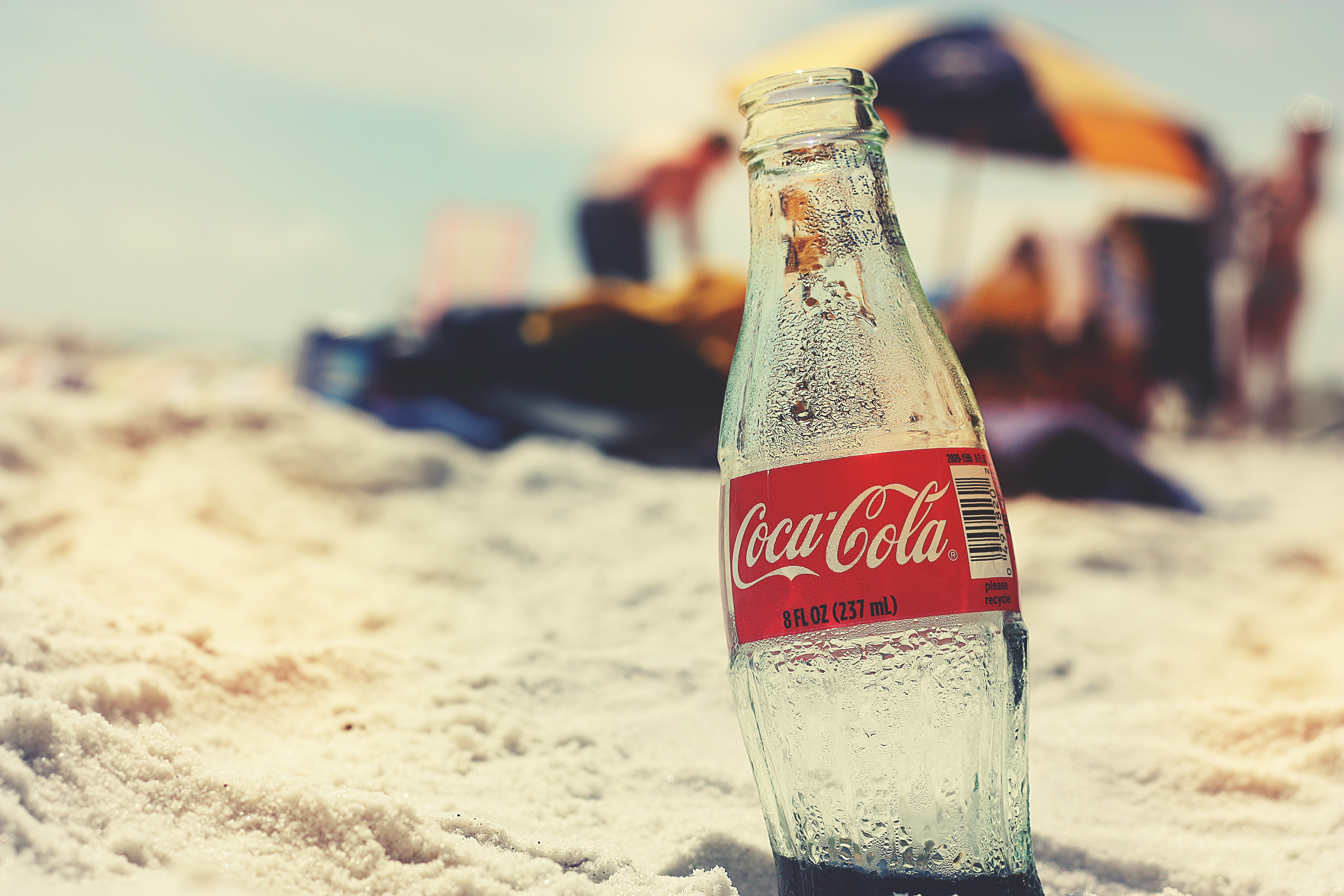 Free photo A bottle of cola buried in the sand.