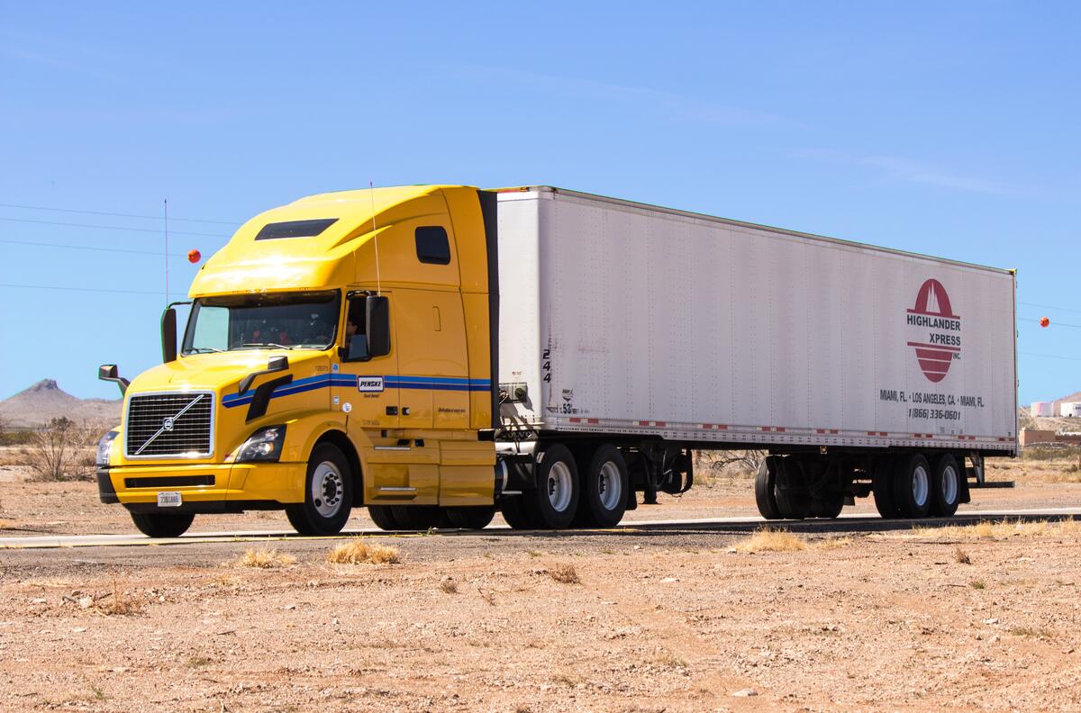 A yellow Volvo truck with a semi-trailer.