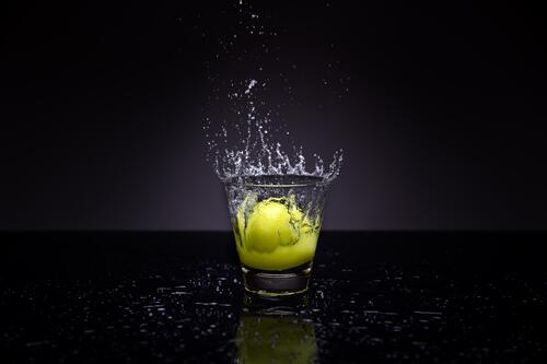 Half a lemon falling into a glass of water.