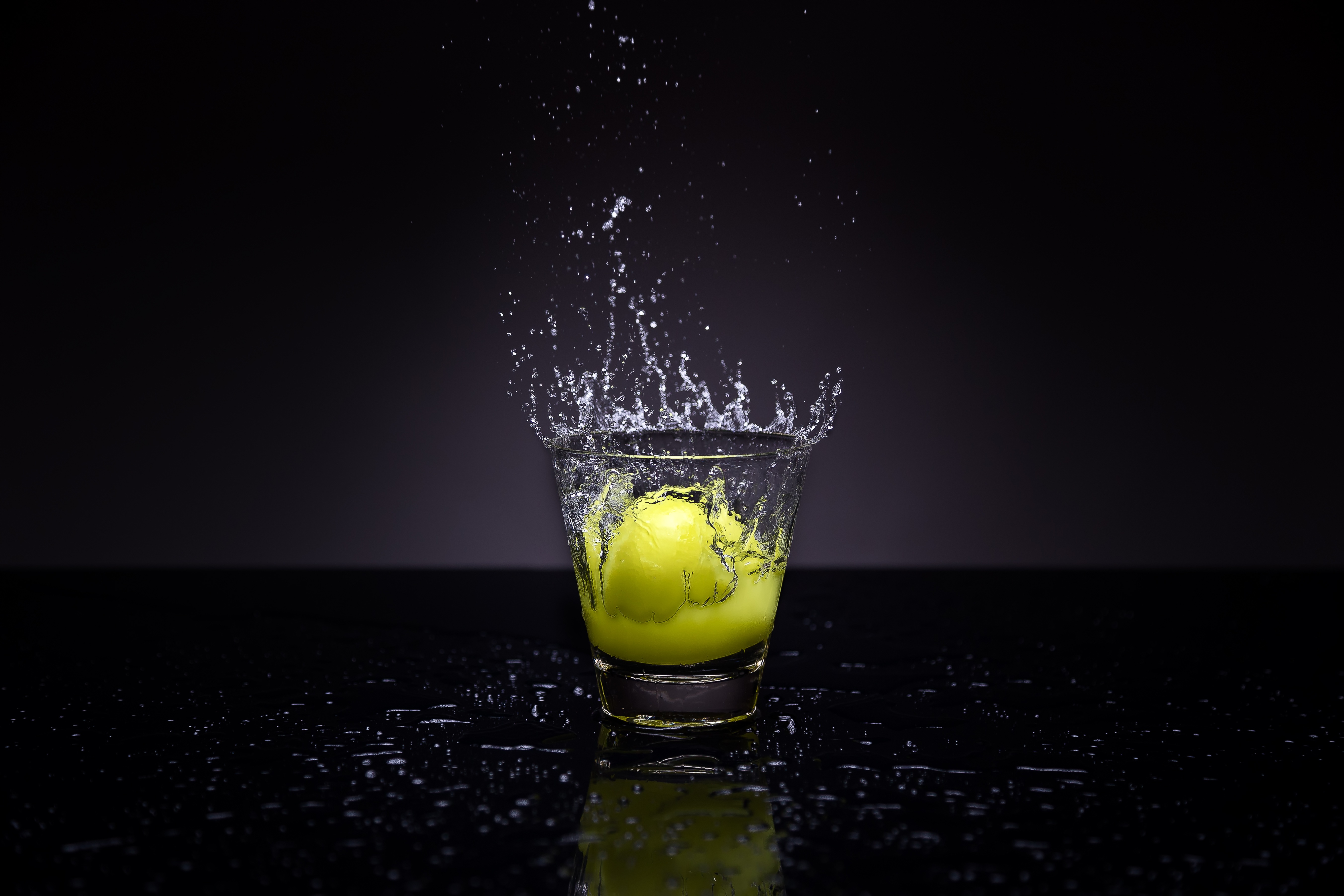 免费照片将半个柠檬倒入一杯水中。