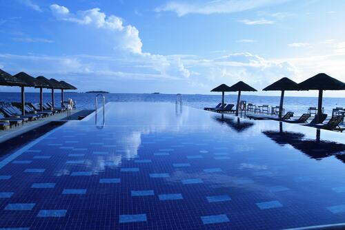 Бассейн на берегу моря с шезлонгами на курорте в Мальдивах